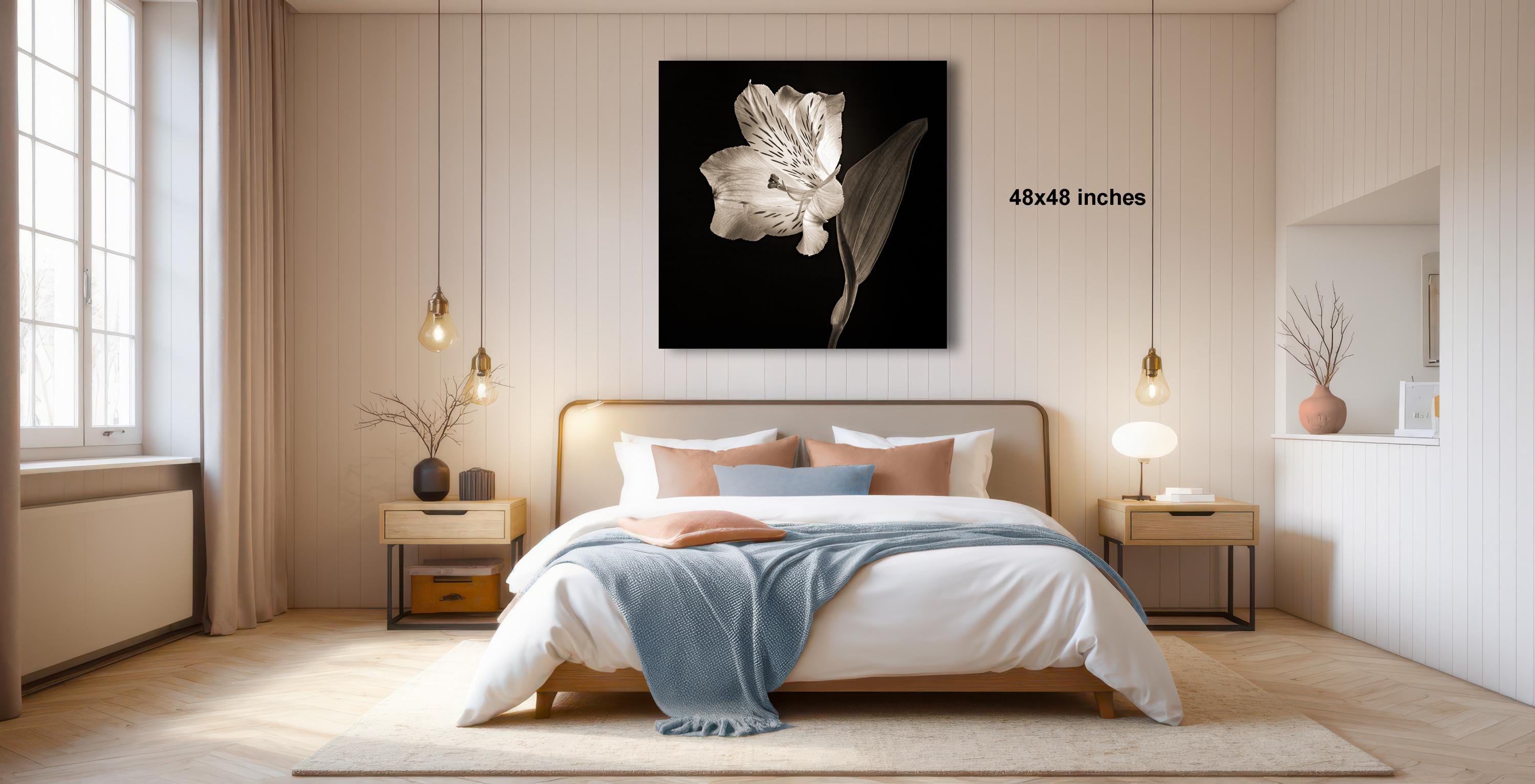 A modern bedroom with a large bed, wooden nightstands, and a large black and white photograph of a flower hanging on the wall.