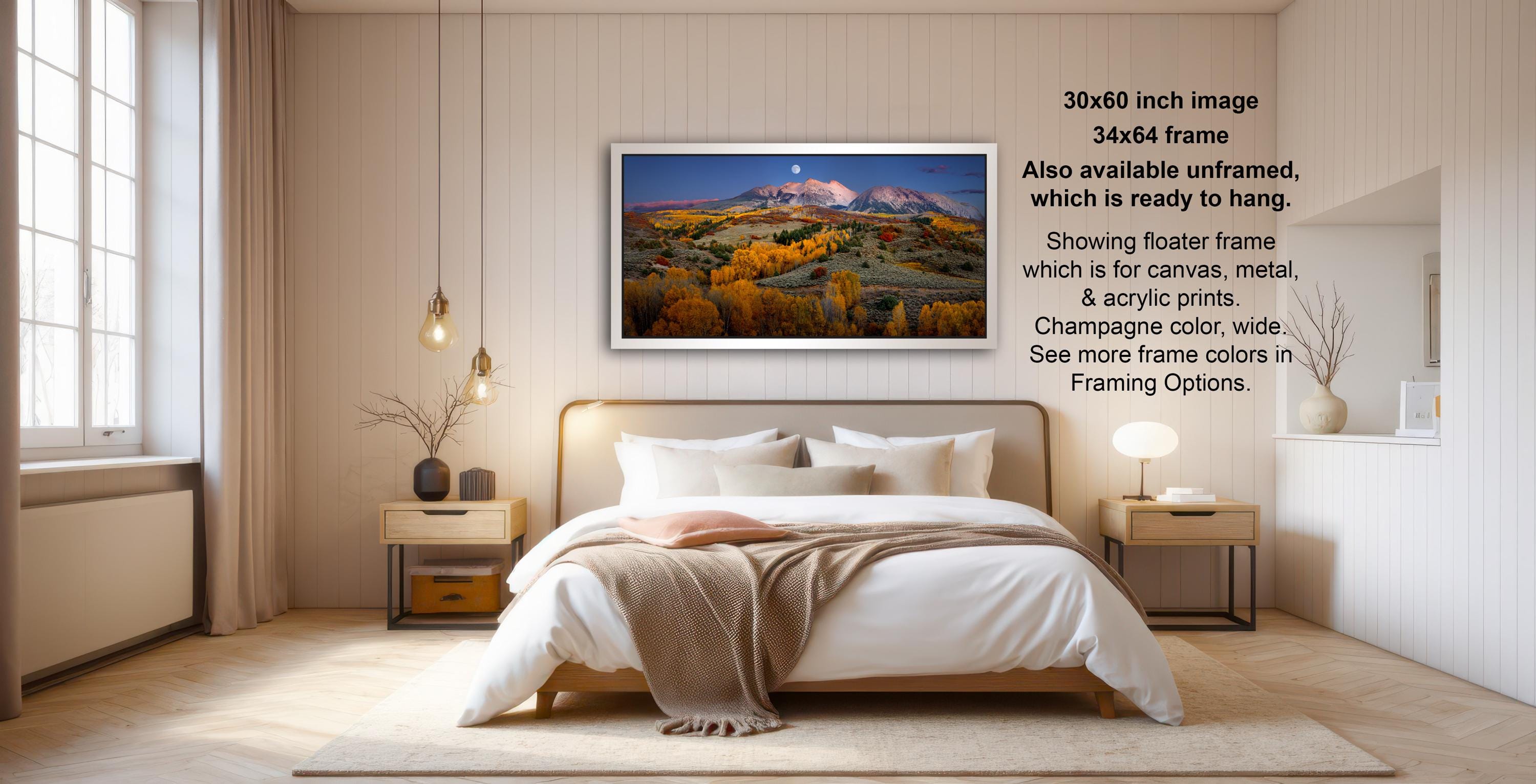The image is a modern bedroom with a large bed, wooden furniture, and a framed landscape photograph hanging on the wall.