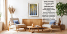 a living room with a framed picture of a forest scene hanging on the wall. The room has two armchairs, a coffee table, and a potted plant, creating a cozy and inviting atmosphere.