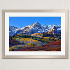 a breathtaking mountain landscape with snow-capped peaks, a vibrant mix of autumnal colors in the foreground, and a serene blue sky above.