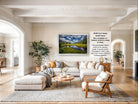 a spacious living room with a large sectional sofa, a coffee table, and a fireplace. The room is decorated with various plants and has a neutral color palette.
