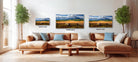 A cozy living room with a large sectional sofa, a coffee table, and three framed landscape paintings hanging on the wall.