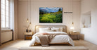 a serene bedroom with a large bed, wooden furniture, and a painting of a lush green field with yellow flowers hanging above it.