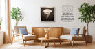 a cozy living room with two beige armchairs, a wooden coffee table, and a framed black and white photograph of a flower on the wall.
