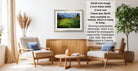 a living room with a framed landscape photograph hanging on the wall, a wooden coffee table in the center, and two chairs facing each other.