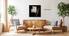 a living room with two beige armchairs, a wooden coffee table, and a wooden sideboard. Above the furniture, there is a framed black and white photograph of a flower on the wall.
