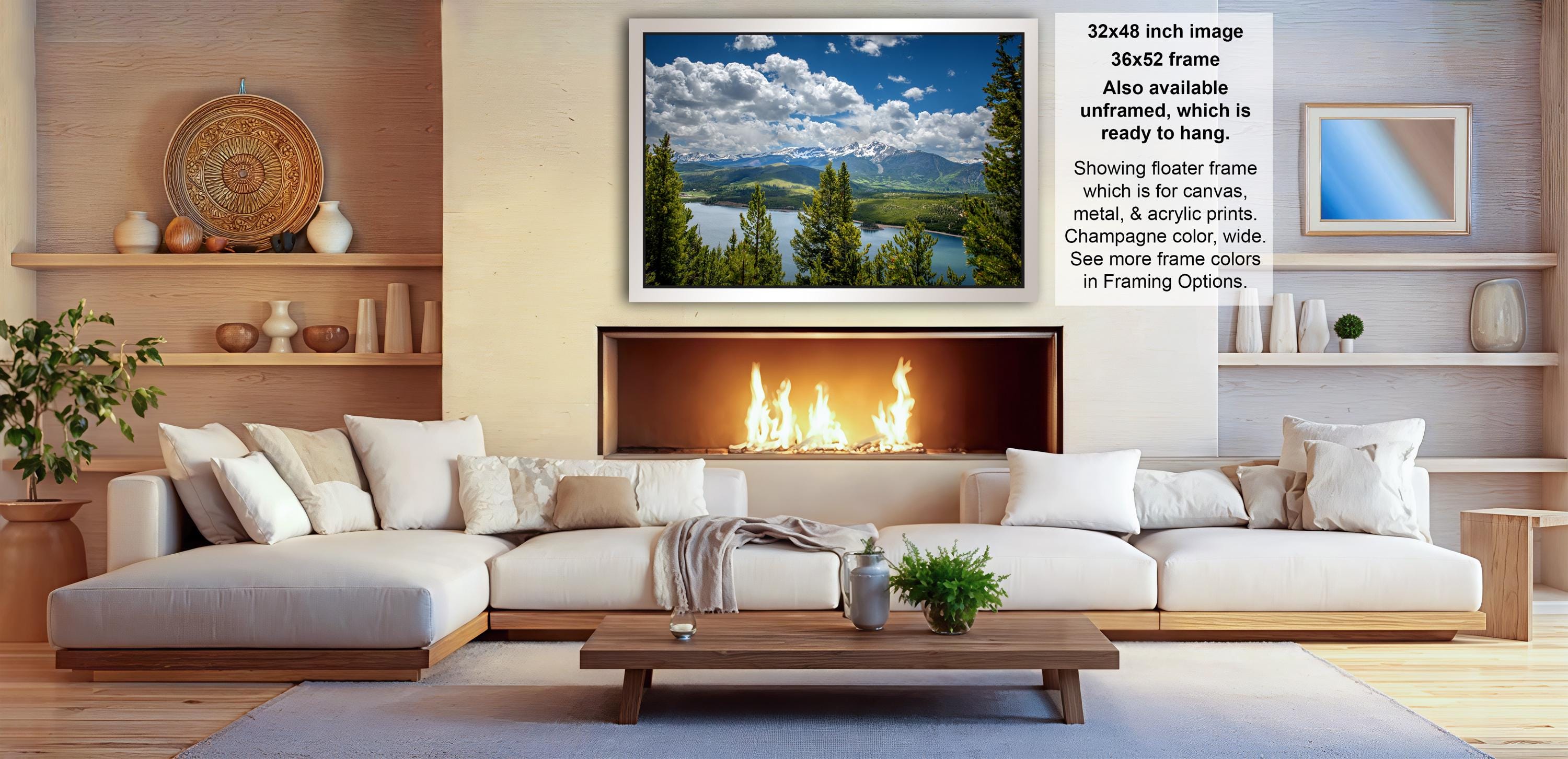 a cozy living room with a fireplace, white sofas, and a large framed landscape painting hanging above it.