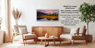 a living room with a wooden coffee table, two white armchairs, and a potted plant. A framed landscape painting is hanging on the wall above the coffee table.