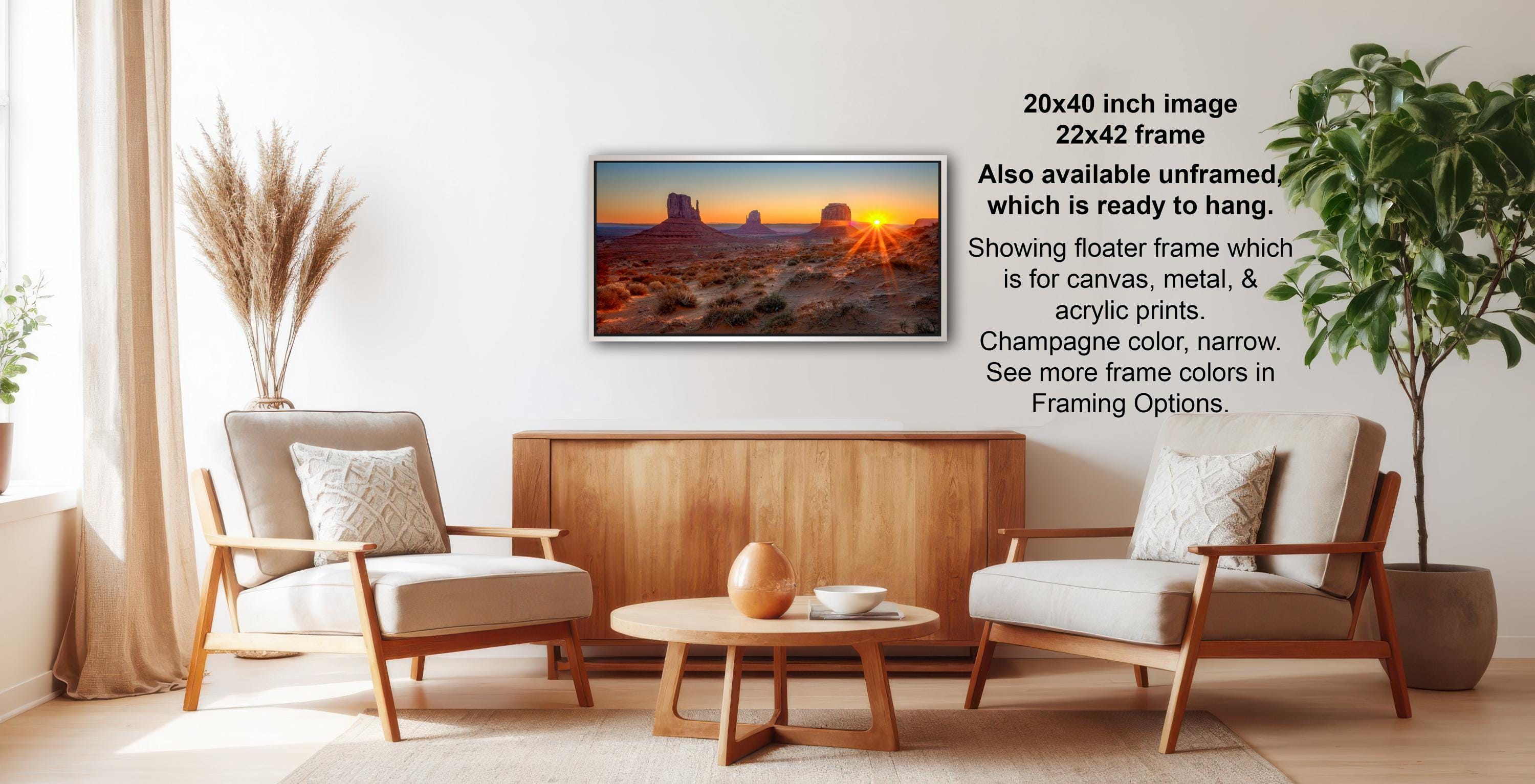 a living room with a wooden coffee table, two white armchairs, and a framed landscape painting hanging on the wall.