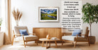 The image is a living room with a framed landscape photograph hanging on the wall, a wooden coffee table in the center, and two chairs facing each other.