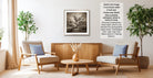 a cozy living room with two comfortable armchairs, a wooden coffee table, and a framed black and white photograph of a tree. The room is decorated with potted plants and a vase of flowers, creating a warm and inviting atmosphere.