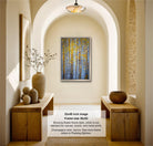 The image is a 32x48-inch framed artwork depicting a forest scene with tall trees and a yellow-leaved canopy. The frame is 36x42 inches and is hanging on a wall in a hallway. The artwork is framed in a wooden frame, and the frame style is described as a foam frame, which is a standard for canvas, acrylic, and metal prints. The colors in the frame are listed as the standard colors for framing, and the artwork is available in frame colors.