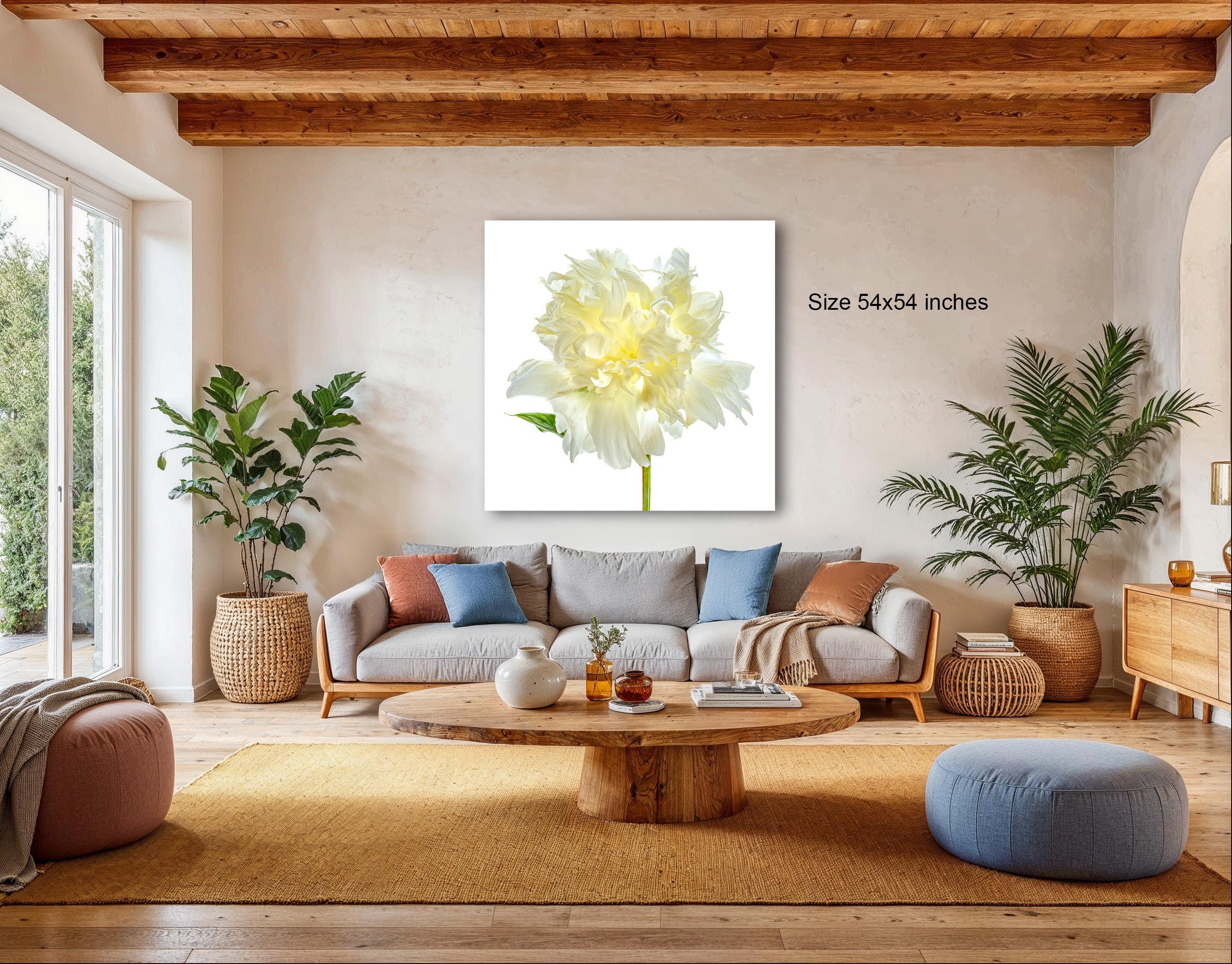 a cozy living room with a large white flower on the wall, a gray sofa, a wooden coffee table, and several potted plants.