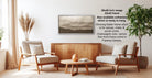 a living room with a wooden coffee table, two beige armchairs, and a framed landscape painting hanging on the wall.