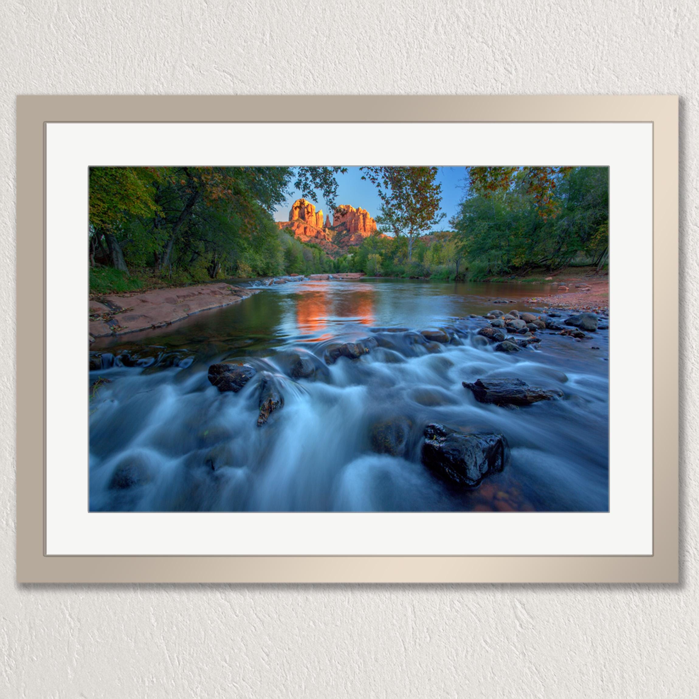 A framed photograph depicting a serene river flowing through a lush, forested landscape, with a large rock formation visible in the distance.