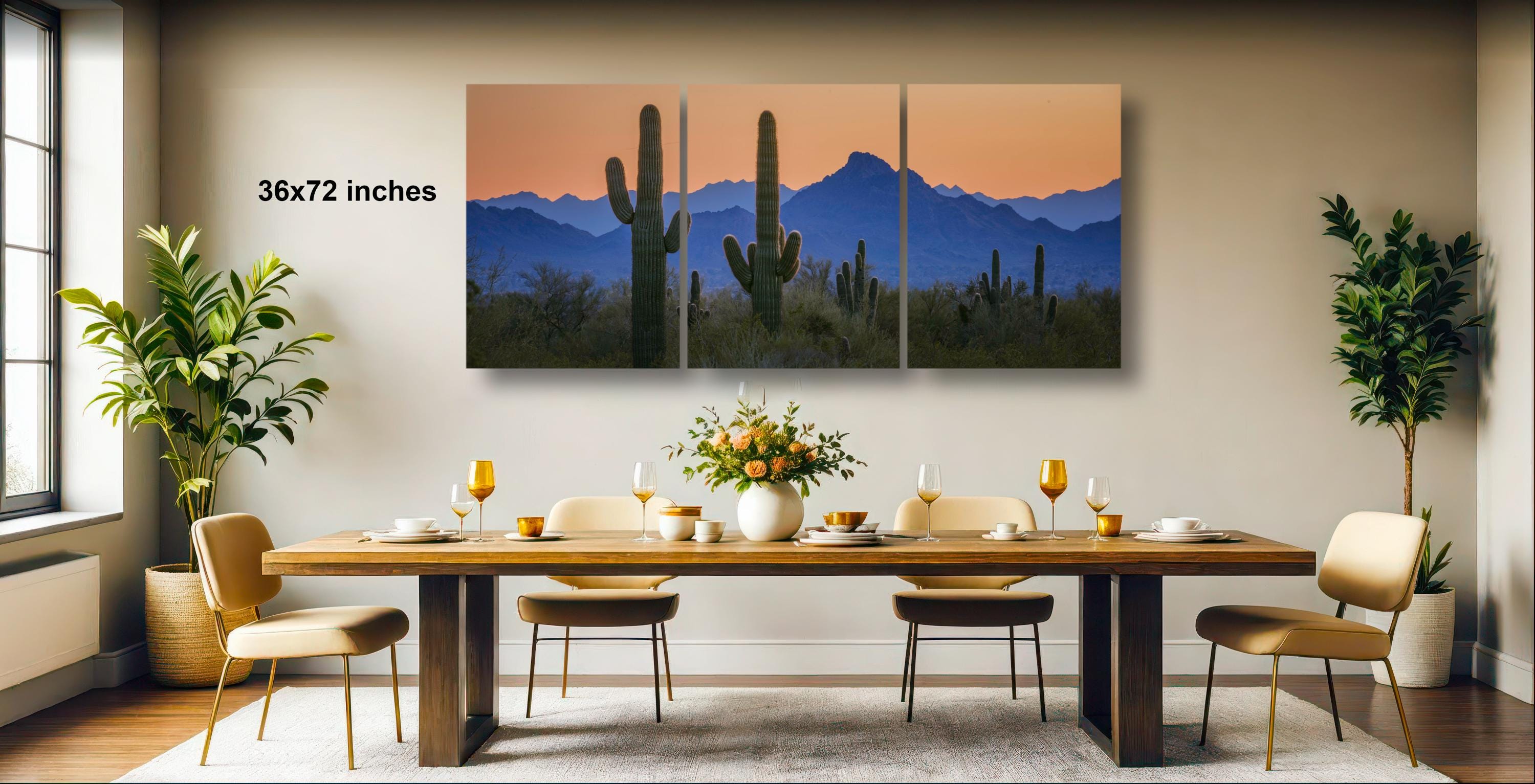 a modern dining room with a large wooden table set for four, surrounded by four chairs. Above the table, there is a large canvas print depicting a desert landscape with cacti and mountains in the background. The room is decorated with potted plants and other modern furnishings, creating a stylish and contemporary atmosphere.