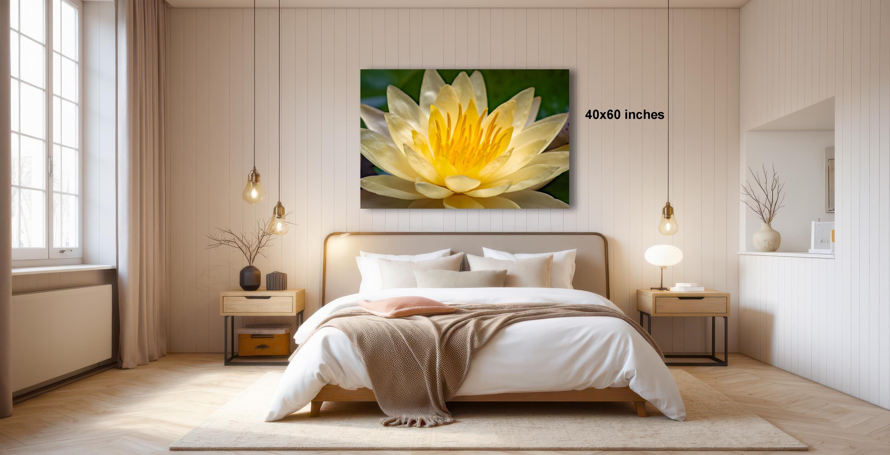 a serene bedroom with a large bed, a nightstand, and a large window. Above the bed, there is a framed picture of a yellow flower. The room has a minimalist and modern design, with white walls and a wooden floor.