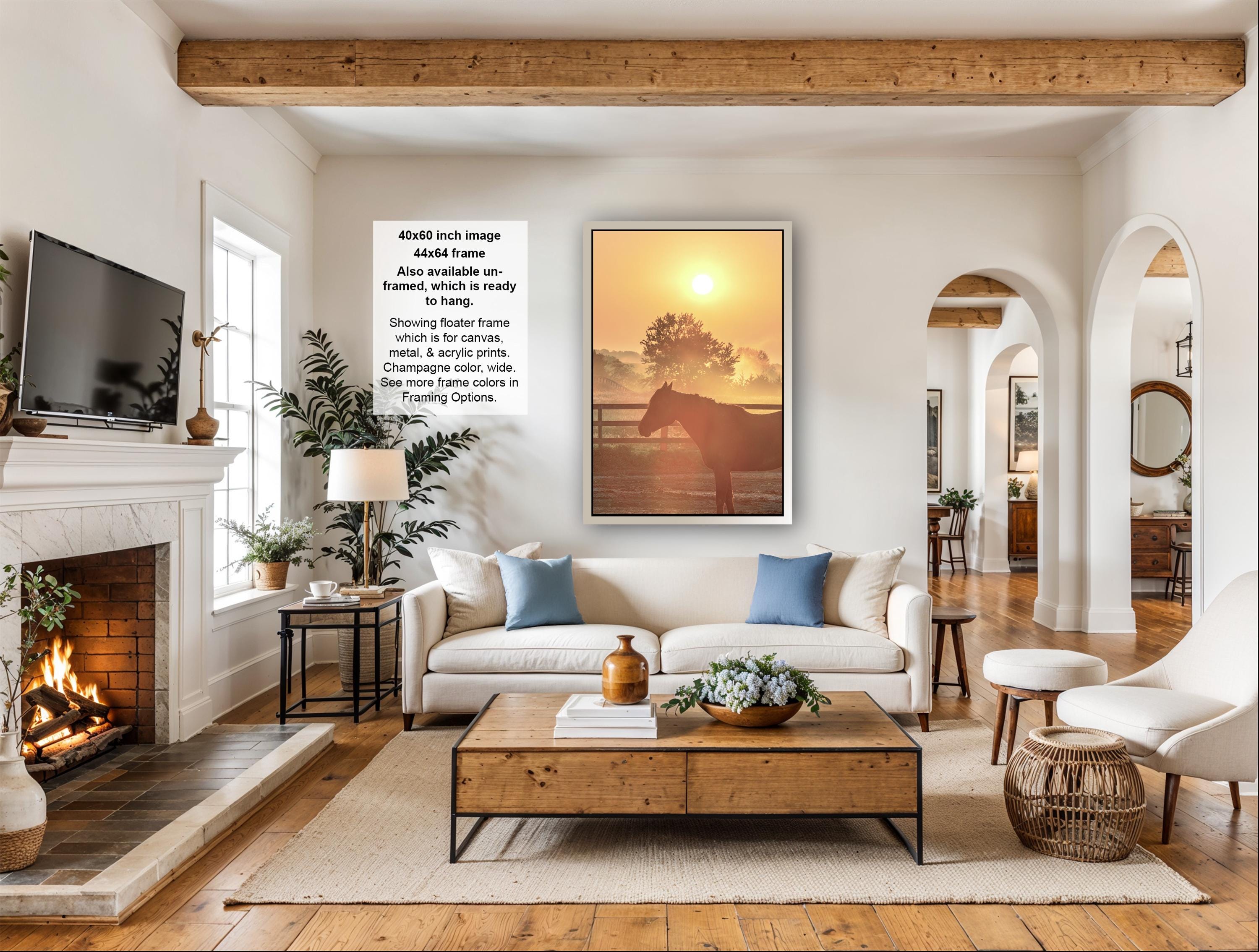 a cozy living room with a fireplace, a large window, a comfortable sofa, a coffee table, and a painting of a horse in a field.
