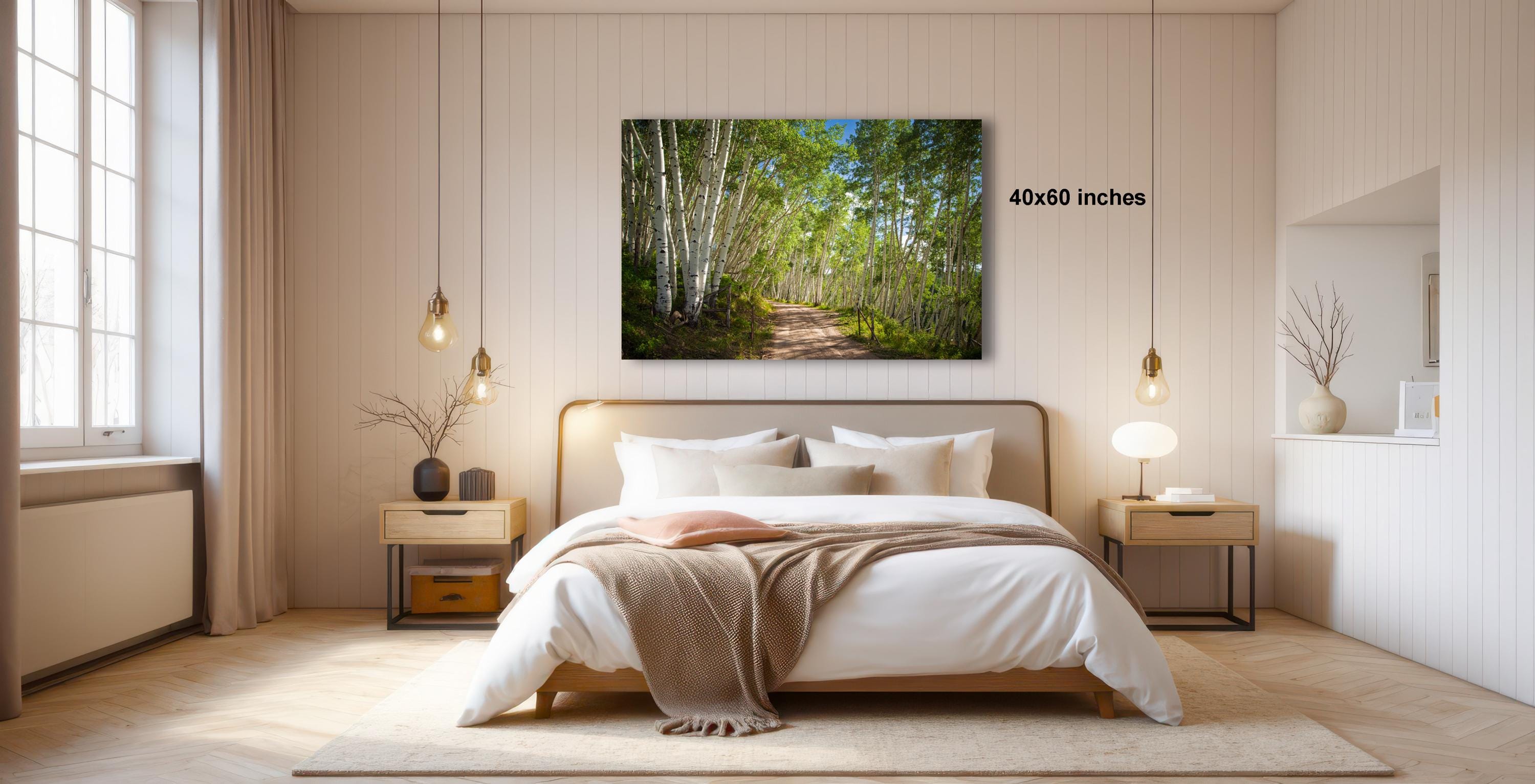 a serene bedroom with a large bed, wooden furniture, and a painting of a forest path on the wall.