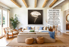 A modern living room with a large framed photograph of a white flower on the wall, a beige sofa, a wooden coffee table, and a potted plant.