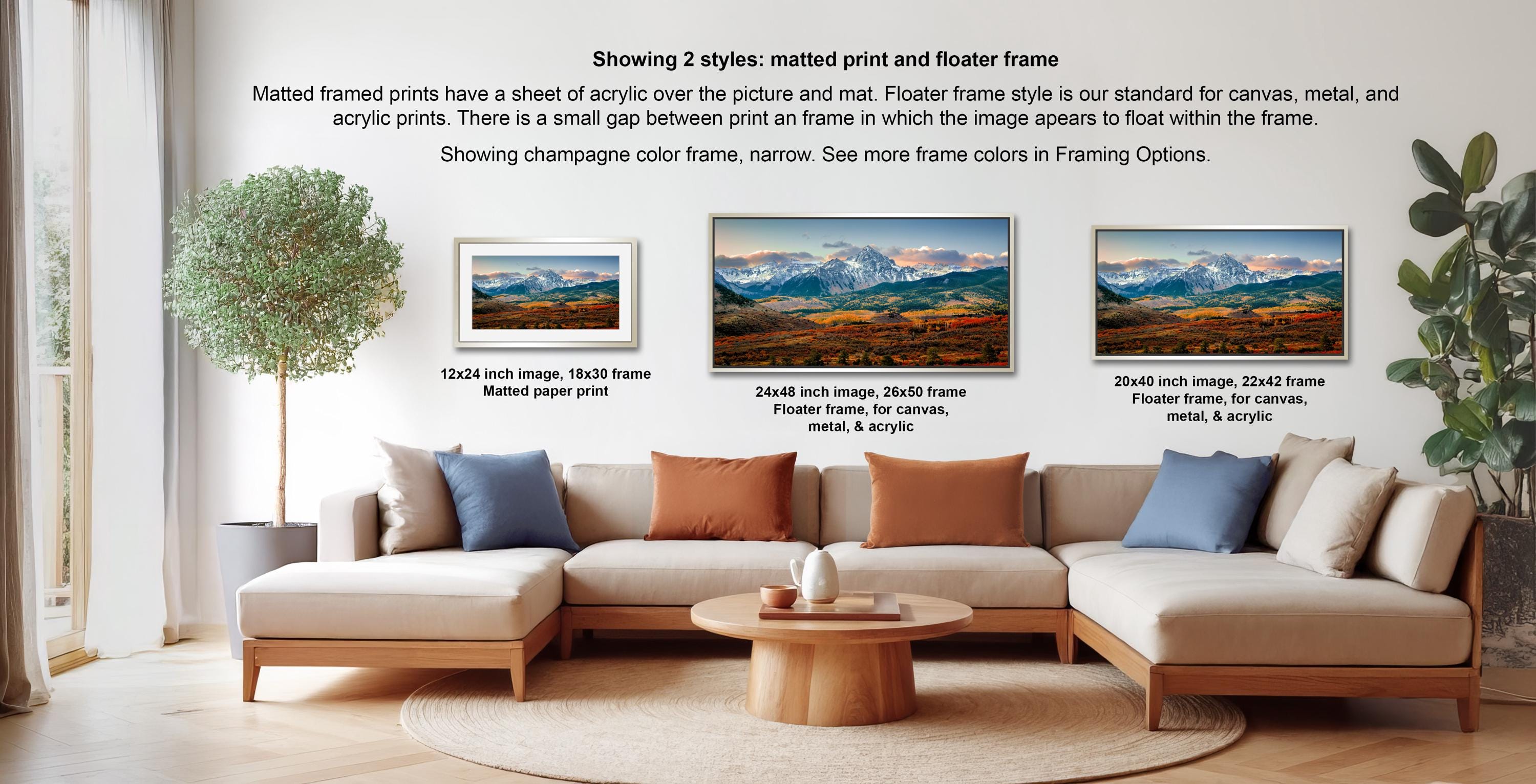 The image is a living room with a large couch and a coffee table, featuring three framed landscape paintings of mountains. The paintings are displayed in different frame styles, including a matured print and a floater frame, showcasing the versatility of the artwork.