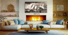 a cozy living room with a fireplace, a large framed black and white photograph of a snowy mountain range, and a wooden coffee table in front of the fireplace.