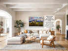 The image is a large framed picture of a desert landscape, hanging on a wall in a living room.