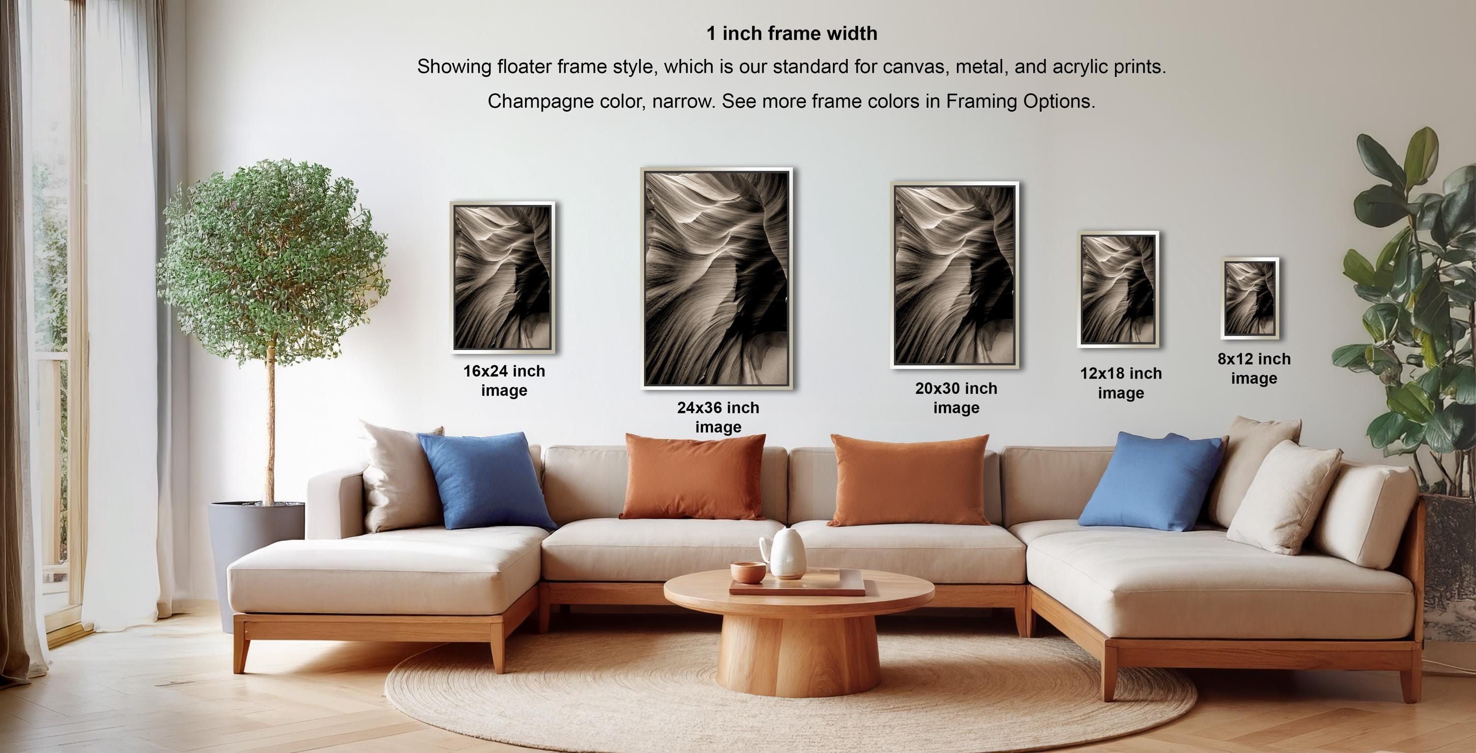 a modern living room with a large sectional sofa, a coffee table, and a potted plant. The sofa is positioned in front of a wall with framed artworks displayed above it. The artworks vary in size and frame style, with some being larger and flatter, while others are smaller and more ornate. The room has a minimalist and contemporary design, with a focus on clean lines and neutral colors.