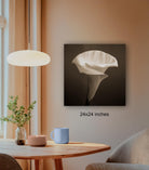 a wooden table with a blue mug, a plant, and a candle, along with a large black and white photograph of a flower hanging on the wall.