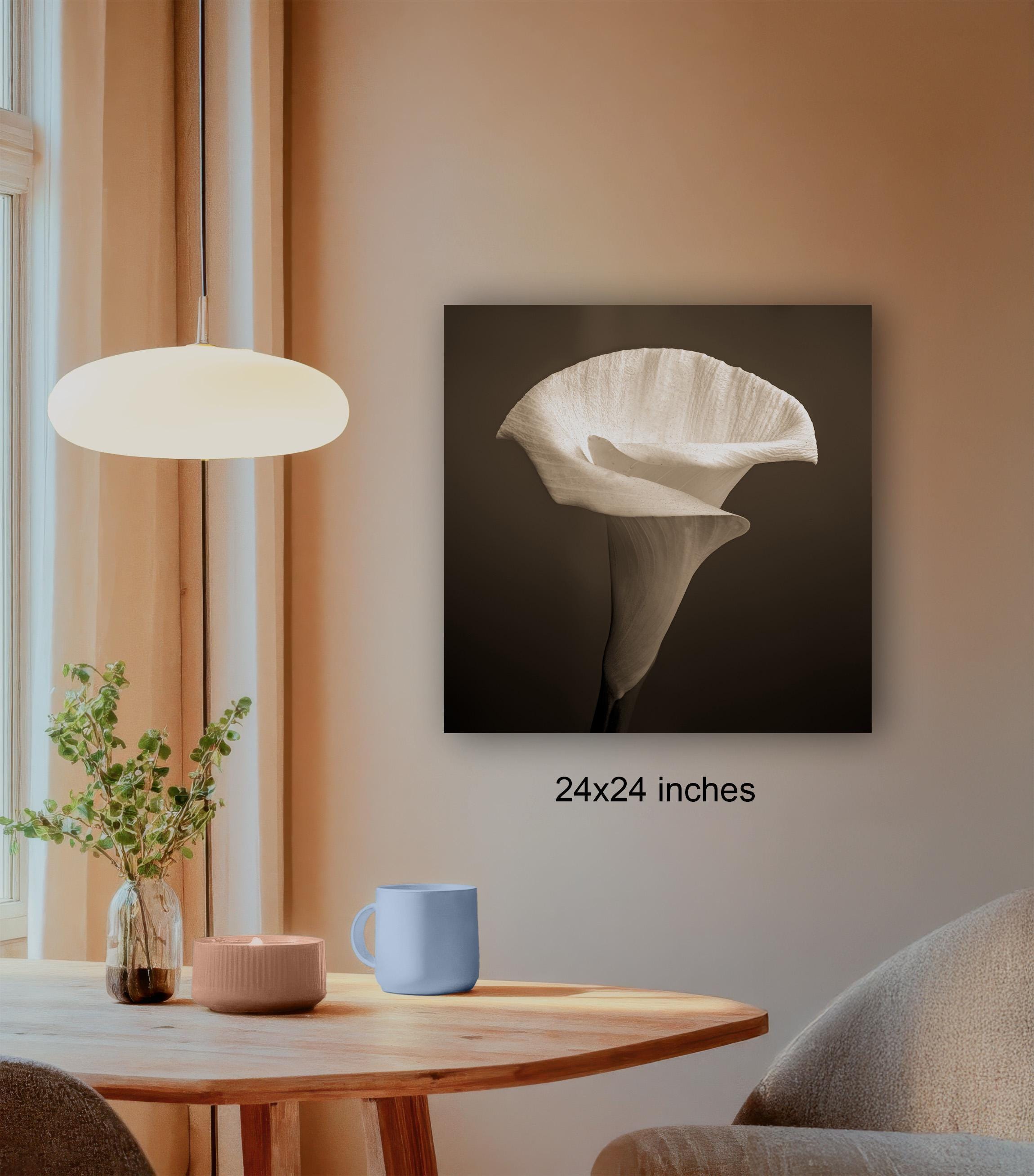 a wooden table with a blue mug, a plant, and a candle, along with a large black and white photograph of a flower hanging on the wall.