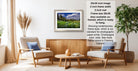 a living room with a framed landscape photograph hanging on the wall, a wooden coffee table in the center, and two armchairs facing each other.