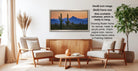 a living room with a wooden coffee table, two white armchairs, and a framed landscape painting of a desert scene with cacti and mountains in the background.