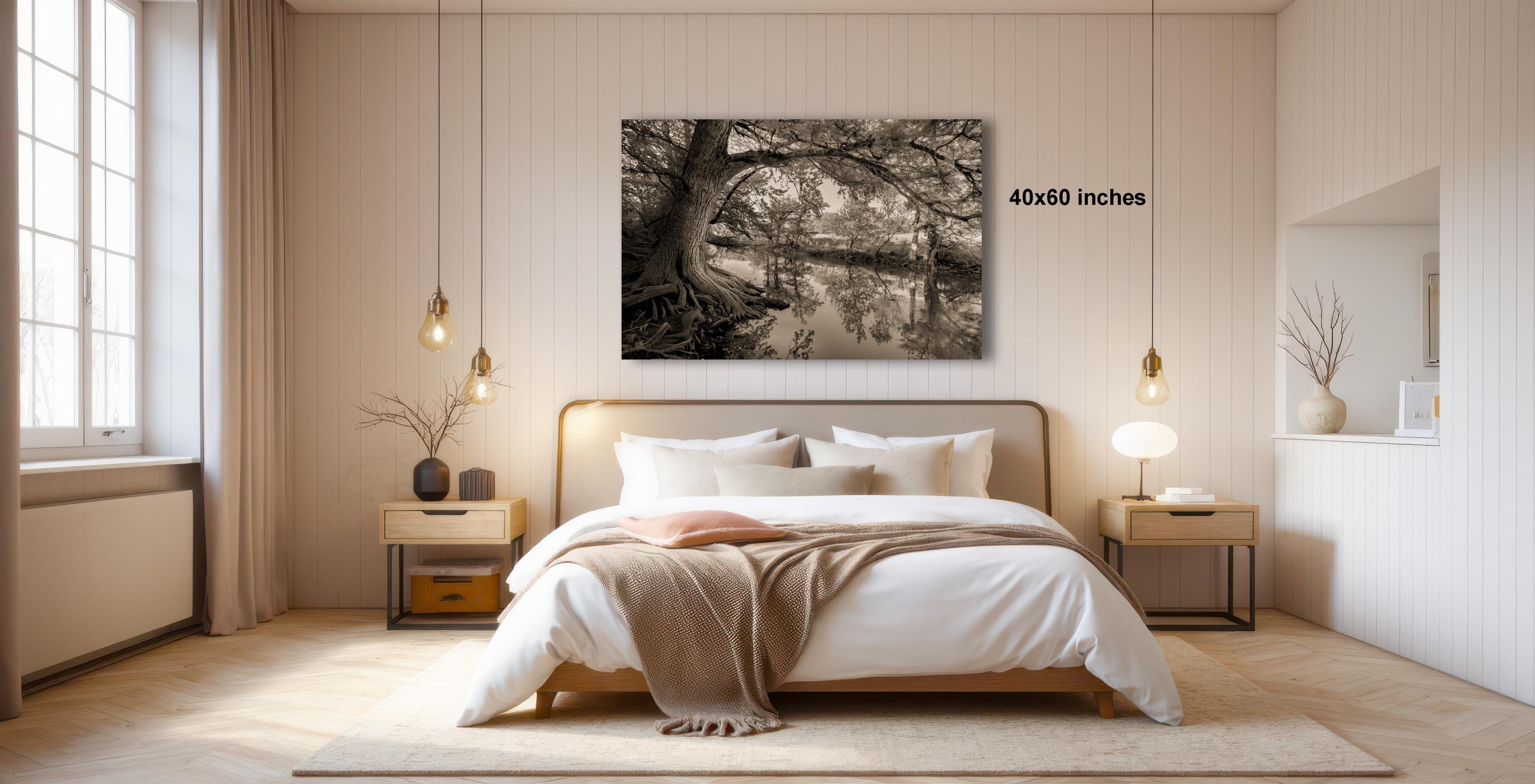 a serene bedroom with a large bed, wooden furniture, and a black and white photograph of a tree on the wall.