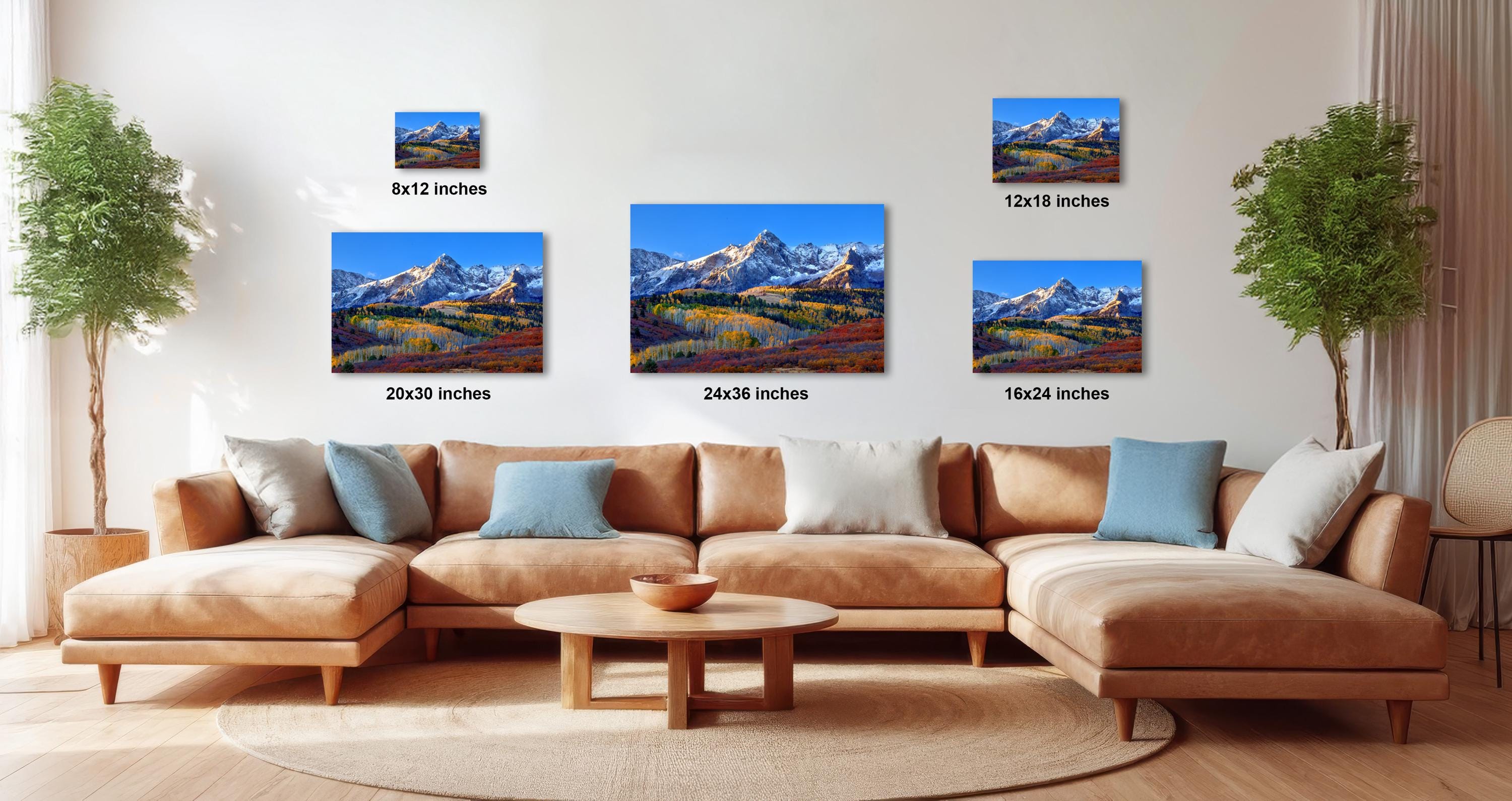 a living room with a large sectional sofa, a coffee table, and several framed landscape paintings displayed on the wall.