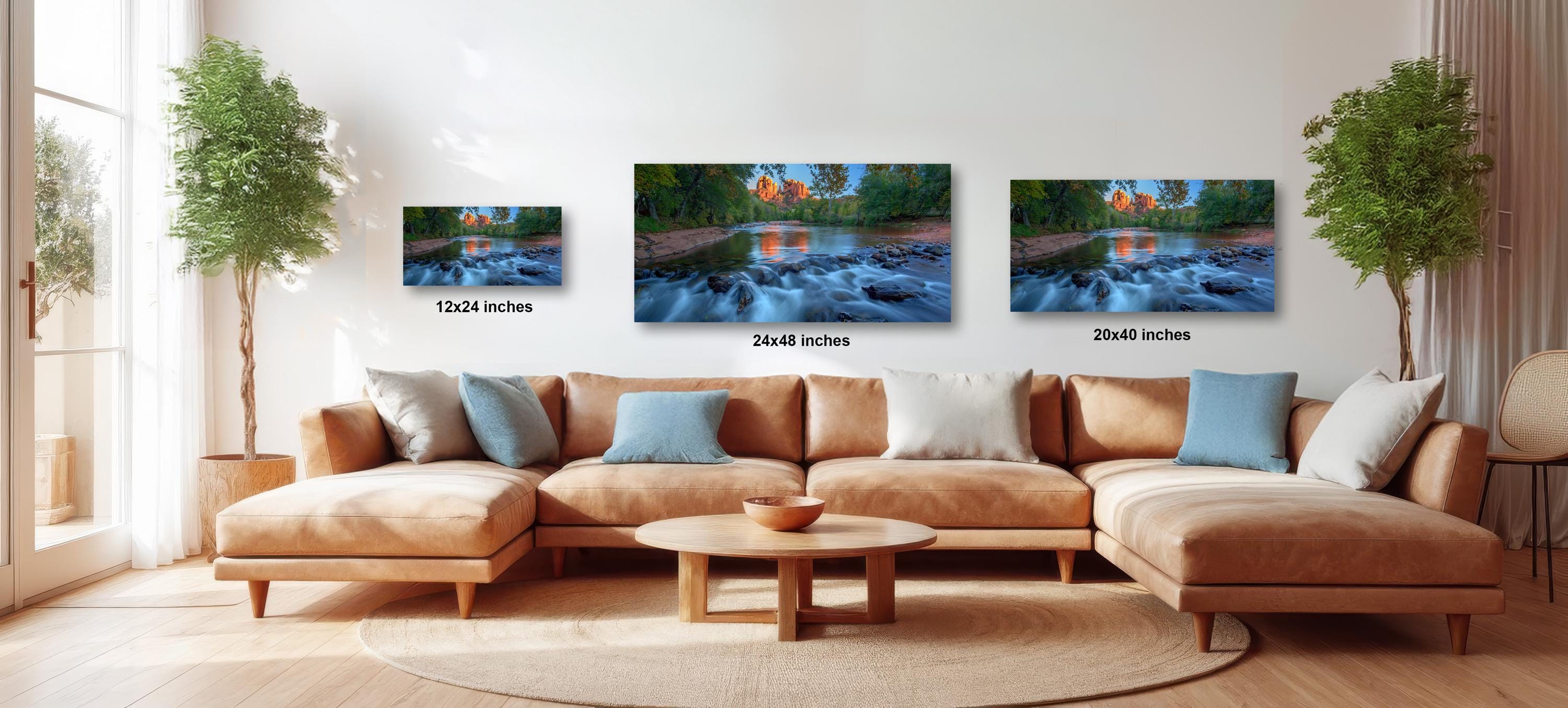 A cozy living room with a large sectional sofa, a coffee table, and three framed landscape paintings hanging on the wall.