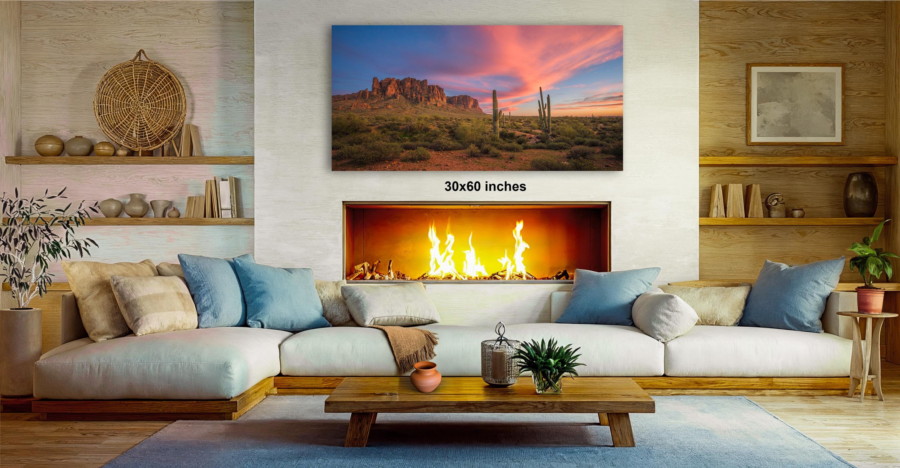 a cozy living room with a fireplace, a large framed landscape painting depicting a desert scene, and a wooden coffee table in front of the fireplace.