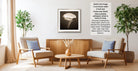 a cozy living room with two beige armchairs, a wooden coffee table, and a framed black and white photograph of a flower on the wall.