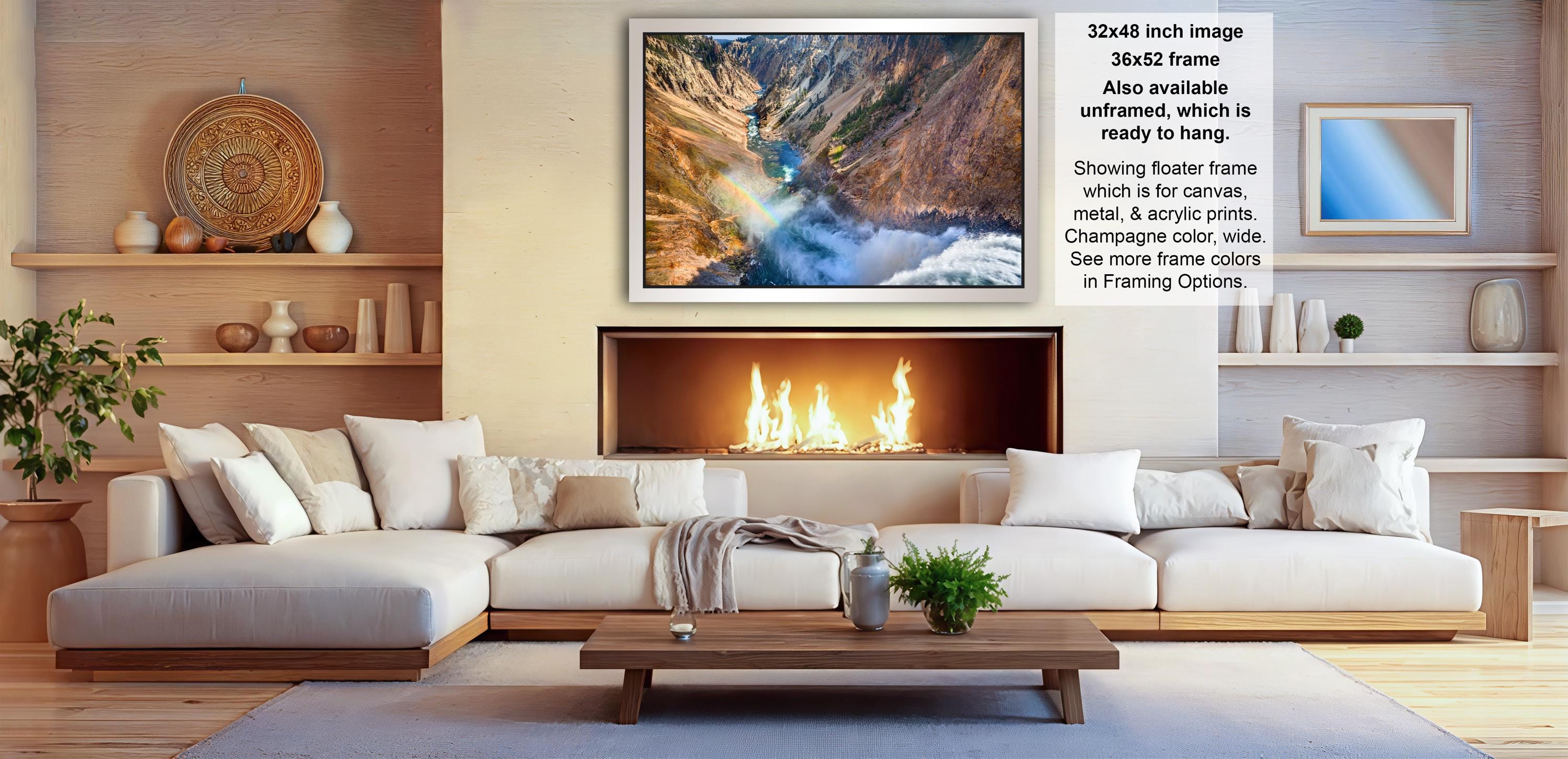 a cozy living room with a fireplace, white sofas, and a coffee table. The room has a warm and inviting atmosphere, with a large framed landscape photograph hanging on the wall above the fireplace.