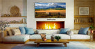 a cozy living room with a fireplace, a large painting of a scenic landscape, and a comfortable couch and coffee table.
