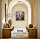 A black and white photograph of a hallway with a framed landscape painting hanging on the wall, flanked by two wooden tables with decorative items on them.
