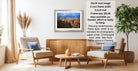 a living room with a framed landscape photograph hanging on the wall, a wooden coffee table in the center, and two chairs facing each other.