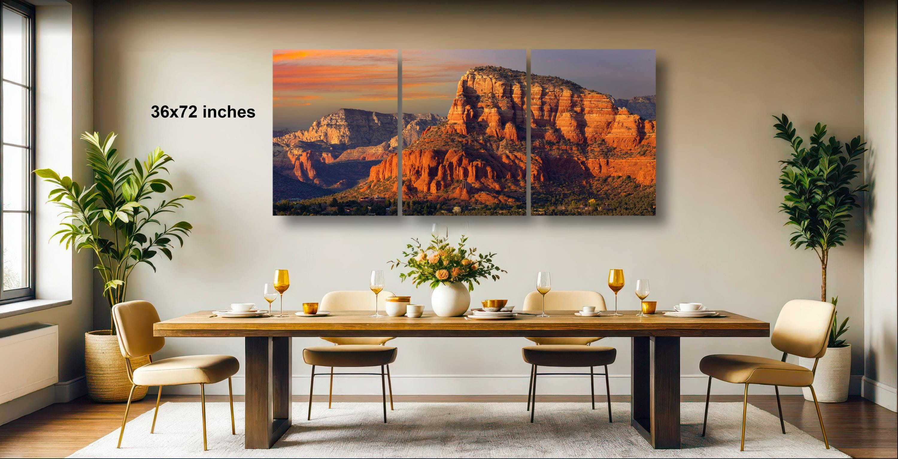 a large, three-panel landscape painting depicting a scenic mountain range at sunset. The painting is hung on a wall above a dining table set with wine glasses, plates, and a vase of flowers. The room has a modern and elegant design, with potted plants and a large window providing natural light.
