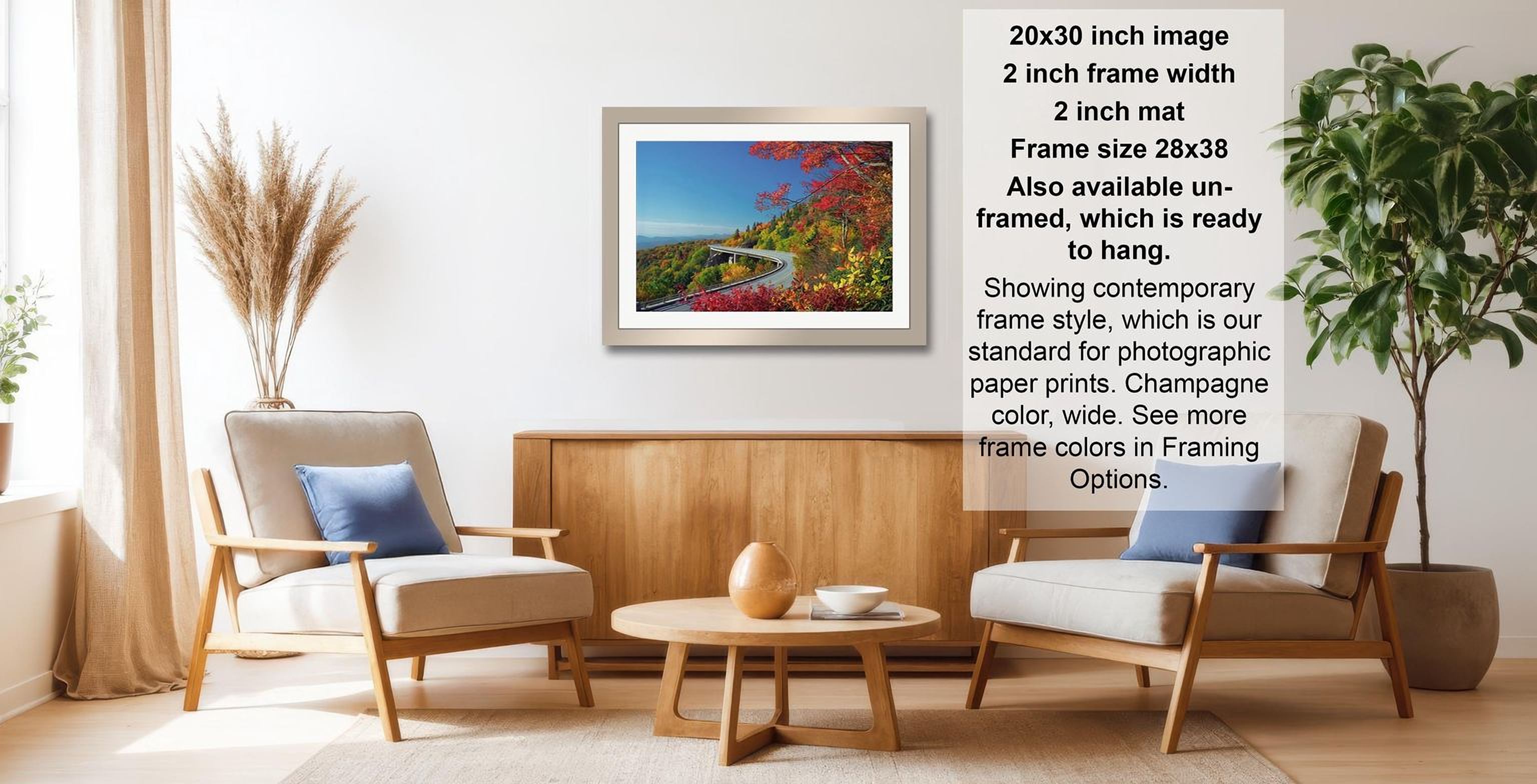 a living room with a framed landscape photograph hanging on the wall, a wooden coffee table in the center, and two chairs facing each other.