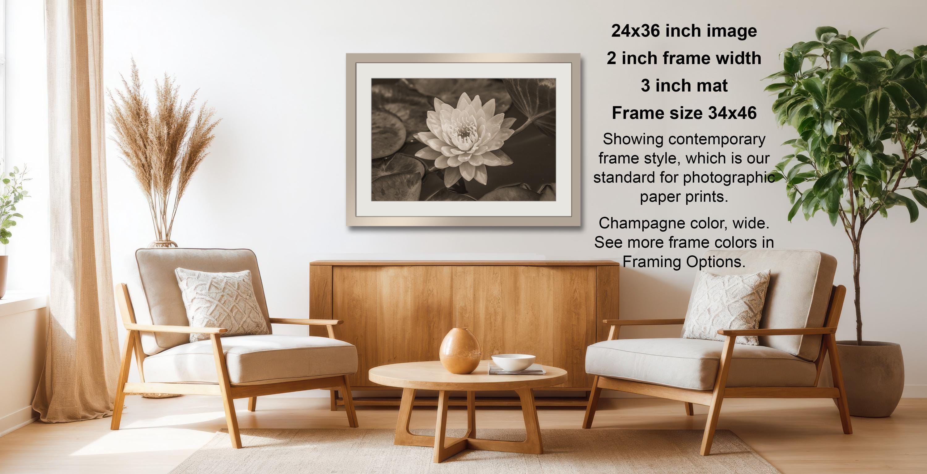 a cozy living room with a wooden coffee table, two beige armchairs, and a framed photograph of a lotus flower hanging on the wall.
