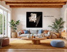 a cozy living room with a large black and white flower on the wall, a comfortable gray sofa, a wooden coffee table, and several potted plants.