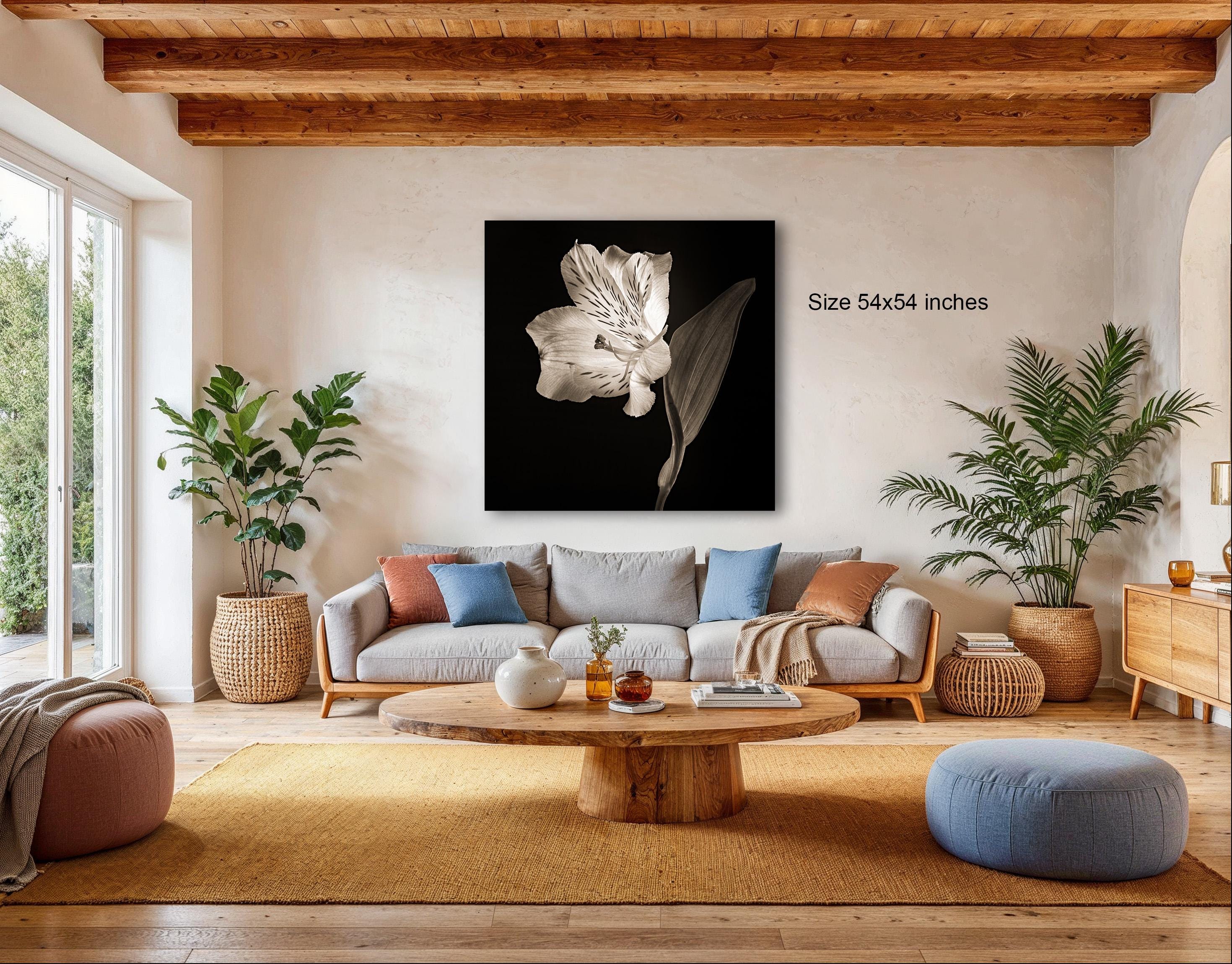 a cozy living room with a large black and white flower on the wall, a comfortable gray sofa, a wooden coffee table, and several potted plants.