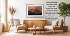 a serene living room with a wooden coffee table, two white armchairs, and a potted plant. The room has a modern and minimalist design, with a large framed photograph of a mountain landscape hanging on the wall.