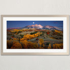 The image is a framed landscape photograph depicting a mountainous, autumnal valley with a full moon in the sky.