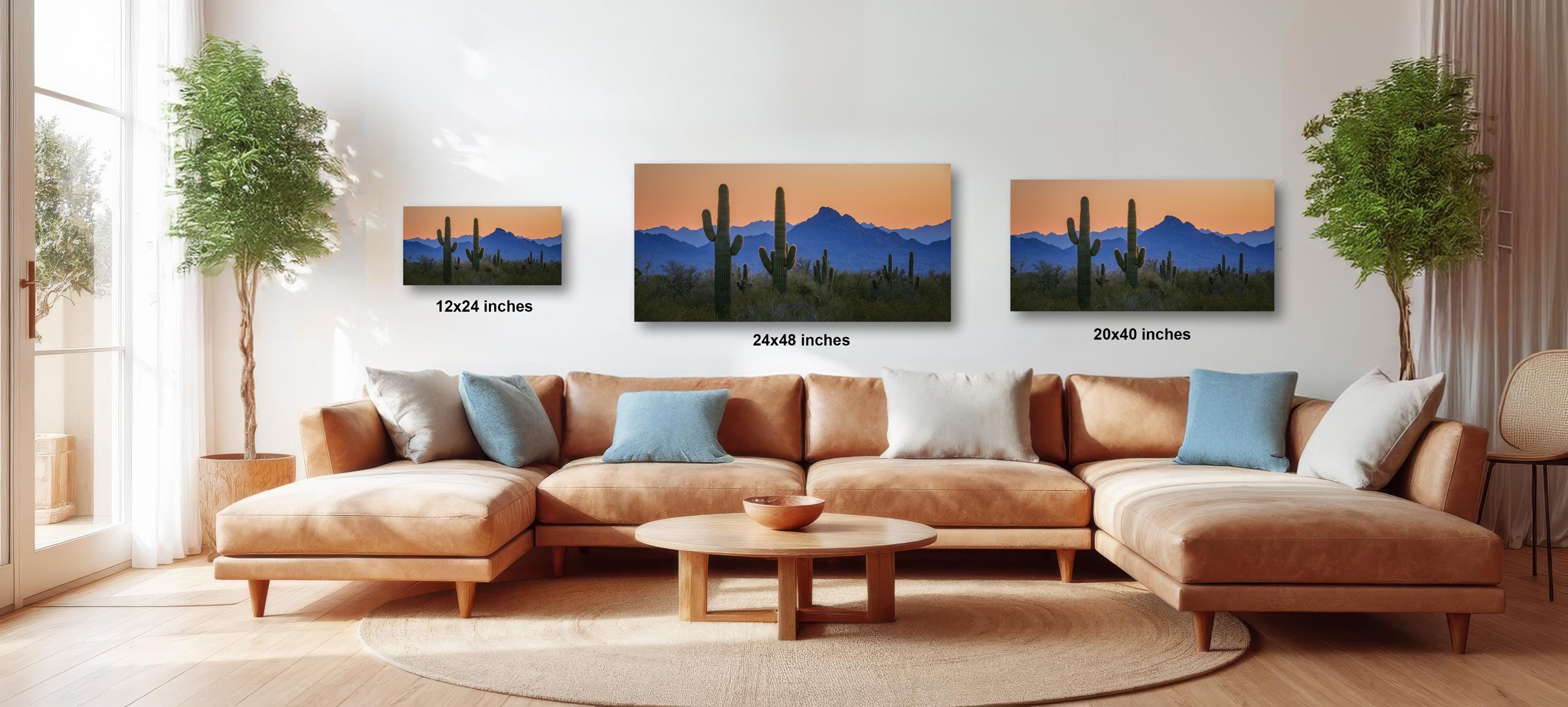 a living room with a large sectional sofa, a coffee table, and three framed landscape paintings of desert scenes on the wall.